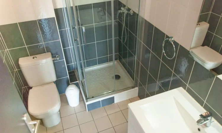 Salle de bain avec WC, douche et lavabo et carrelage blanc et accessoires modernes dans le studio