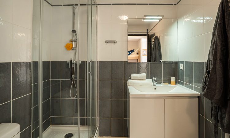 Salle de bain d’un T2 cabine à Hossegor avec douche moderne et aménagement pratique.